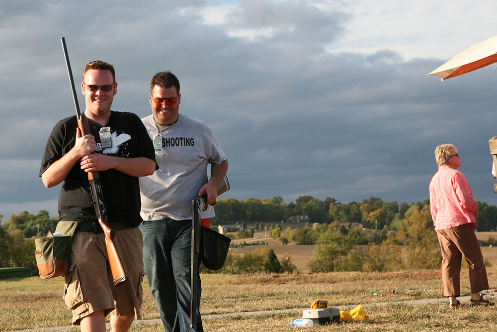 Two smiling shooters with shotguns on the field